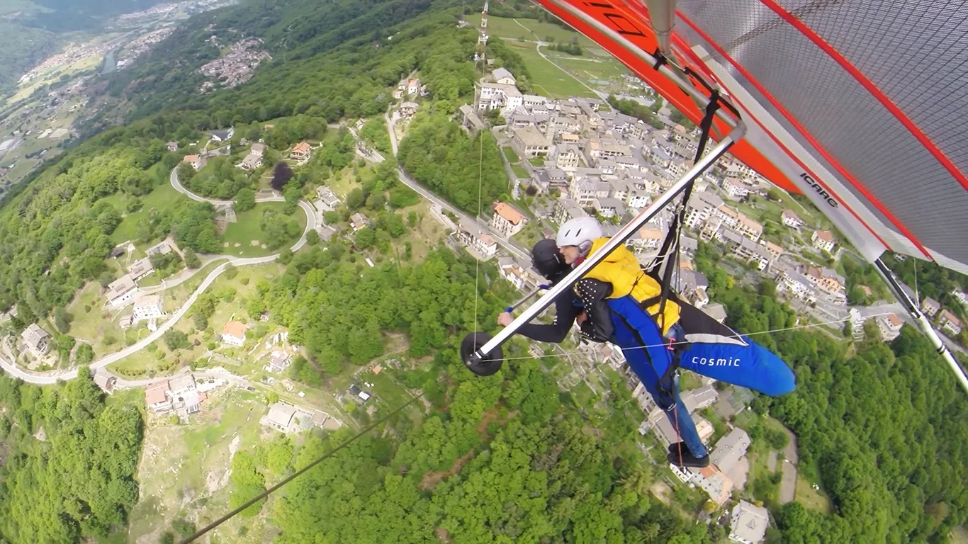 Deltaplano biposto in volo sopra un paesaggio di montagna e lago